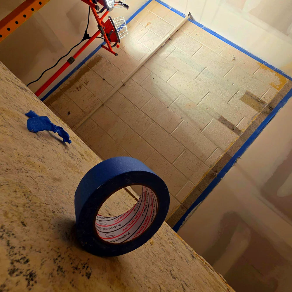 Roll of blue painter's tape in front of a taped block wall